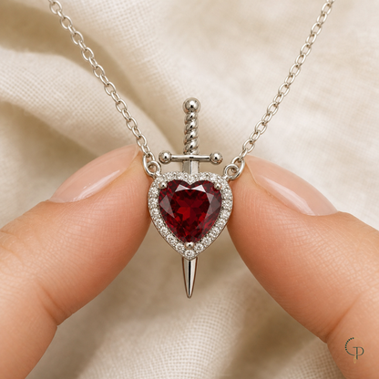 Hand-scale view of the small red heart sword pendant and its two side chain connections