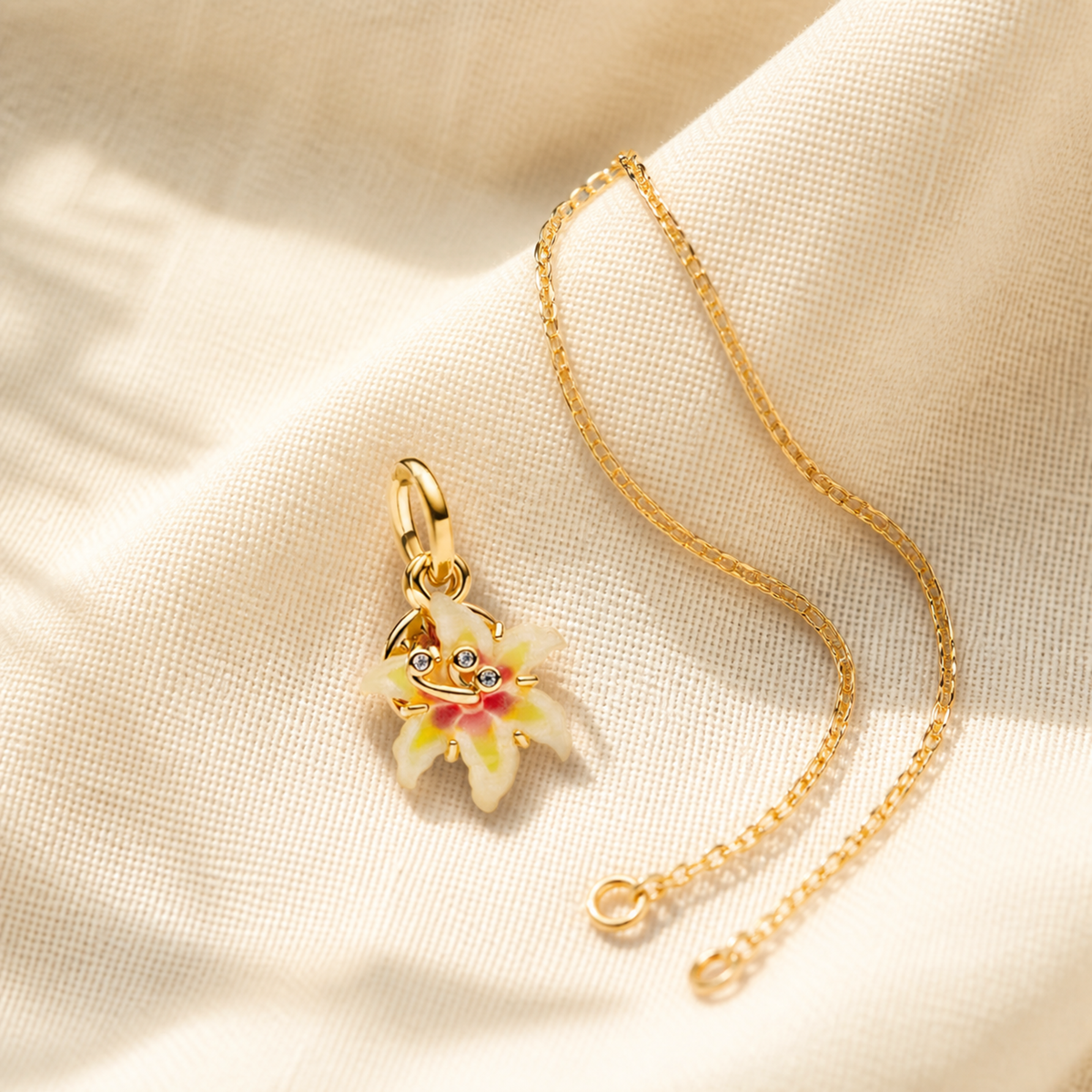 Gold-tone enamel flower charm beside a separate fine chain for styling inspiration