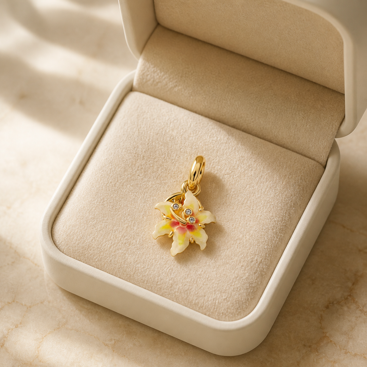 Gold-tone enamel flower pendant charm presented in an ivory jewelry box