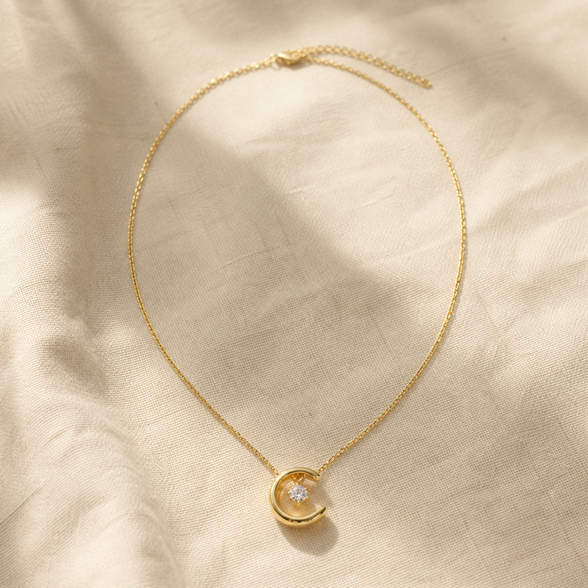Gold-color crescent moon necklace with suspended round crystal
