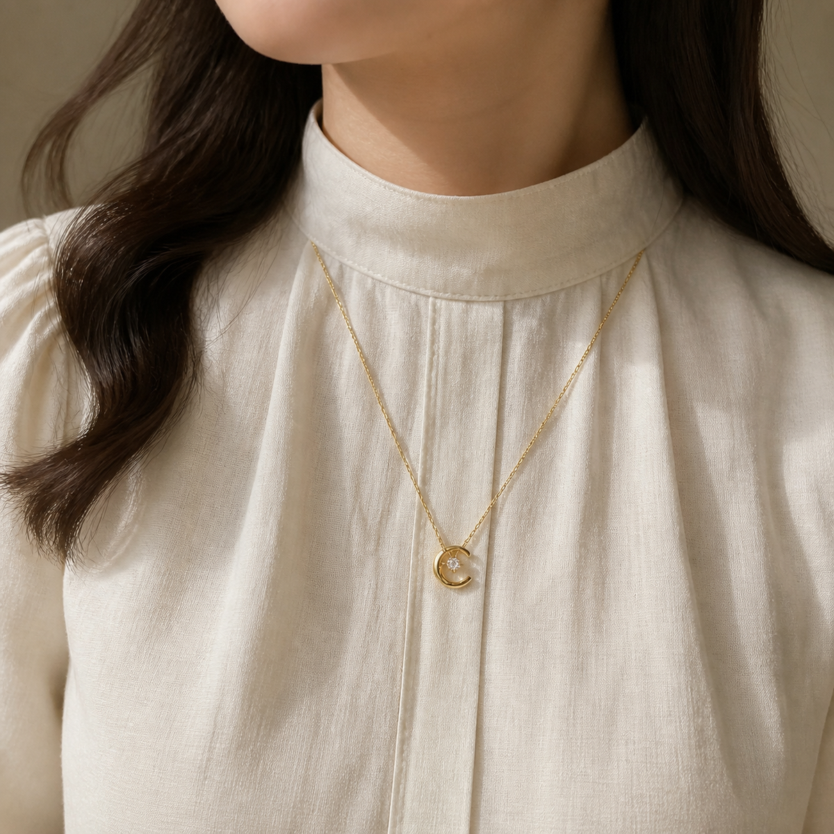 Crescent moon crystal pendant necklace worn with a neutral ivory blouse