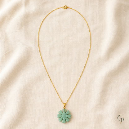 Complete gold-color chain with clasp and seafoam sunburst pendant arranged on ivory linen