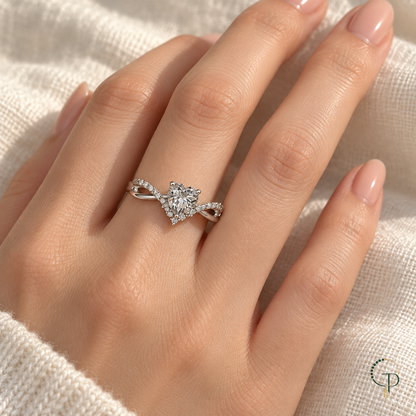 Silver-color heart twist ring worn on a hand against ivory linen.