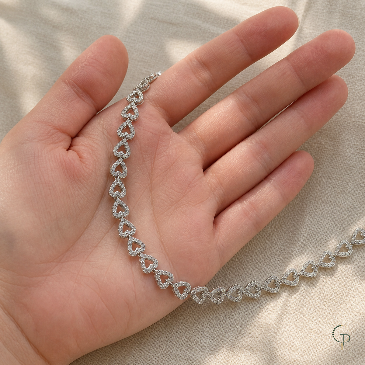Silver-color open heart necklace resting across an open hand for scale