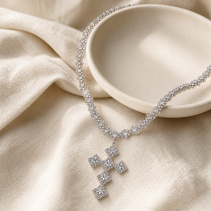 Square cluster cross necklace styled beside an ivory ceramic dish