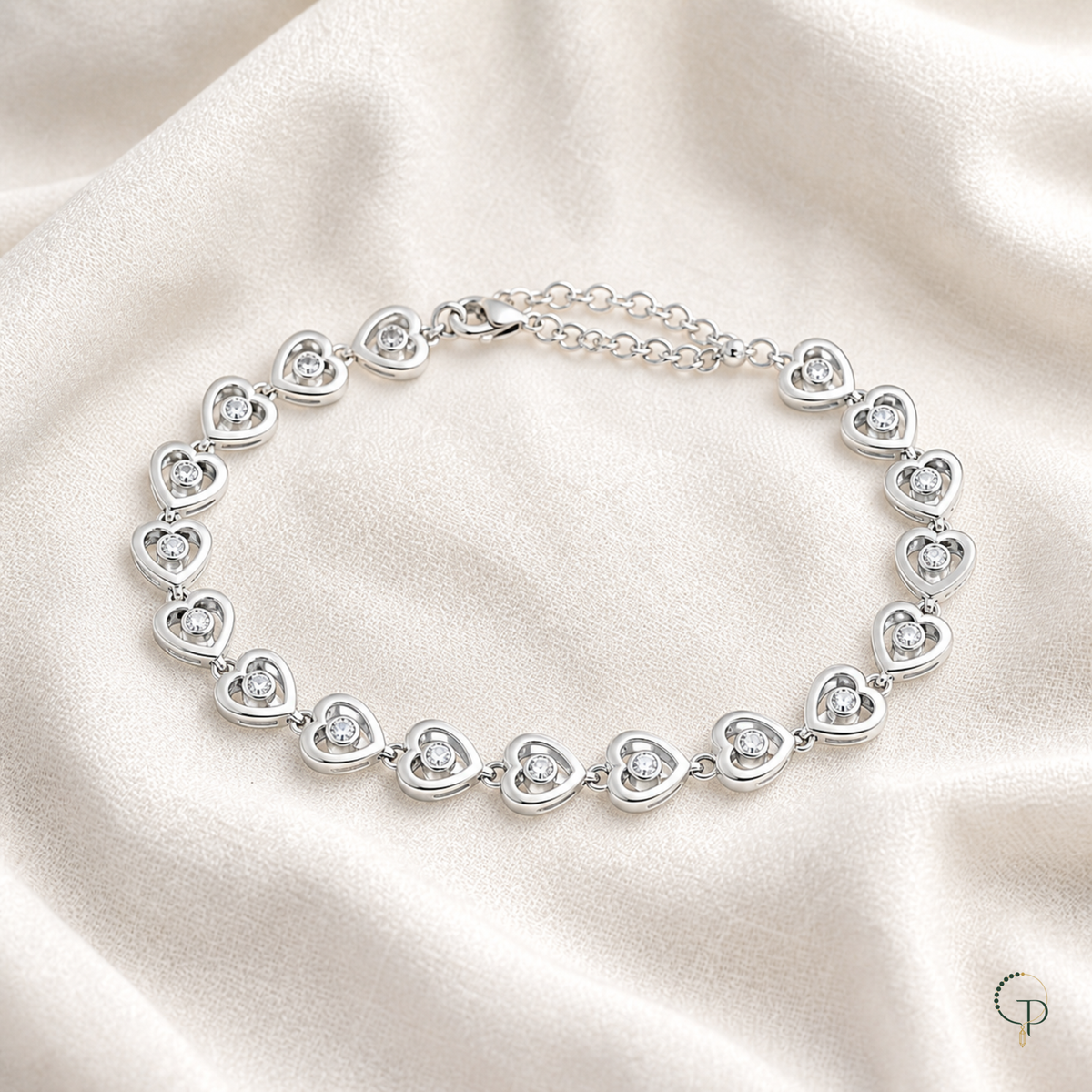 Single-crystal heart link bracelet arranged on ivory linen