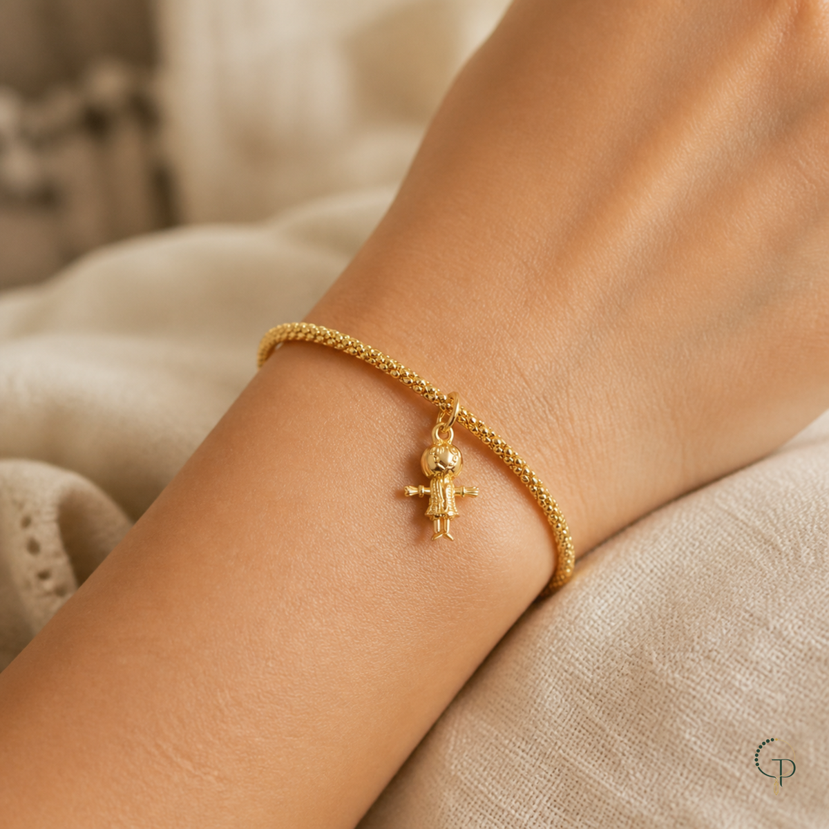 Gold-color little figure charm bracelet worn on wrist