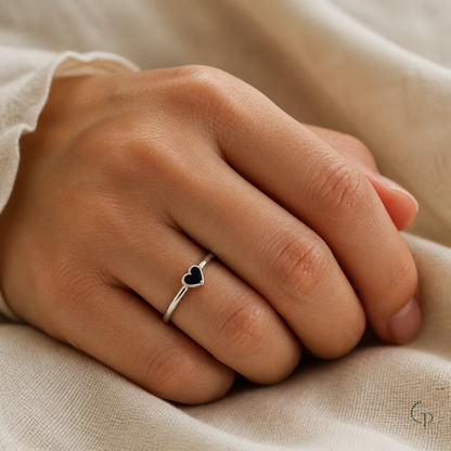 Silver-color petite black heart ring worn on hand