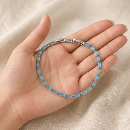Light blue tennis bracelet displayed in a hand for scale