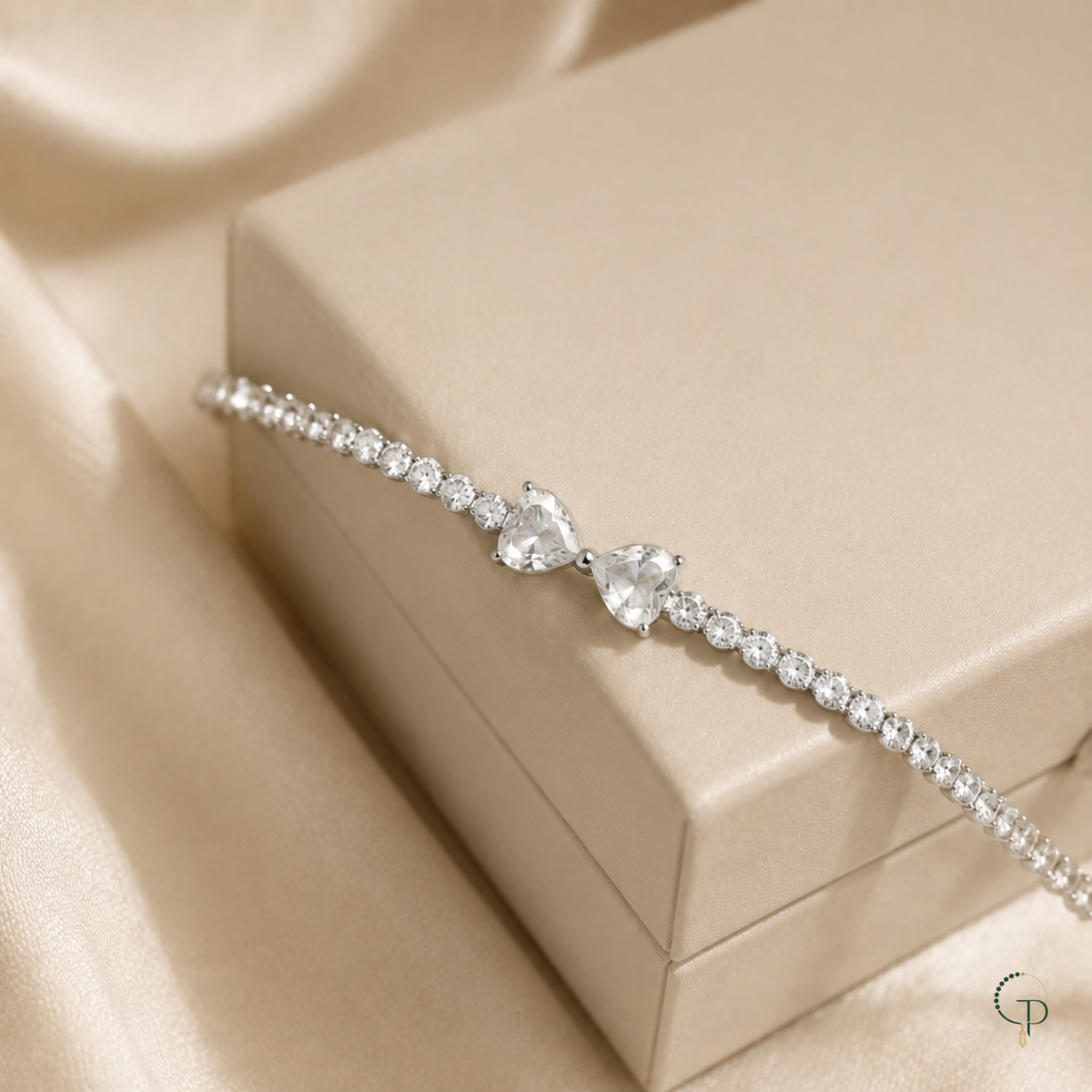 Silver-color twin heart bow tennis bracelet styled across a plain ivory display box