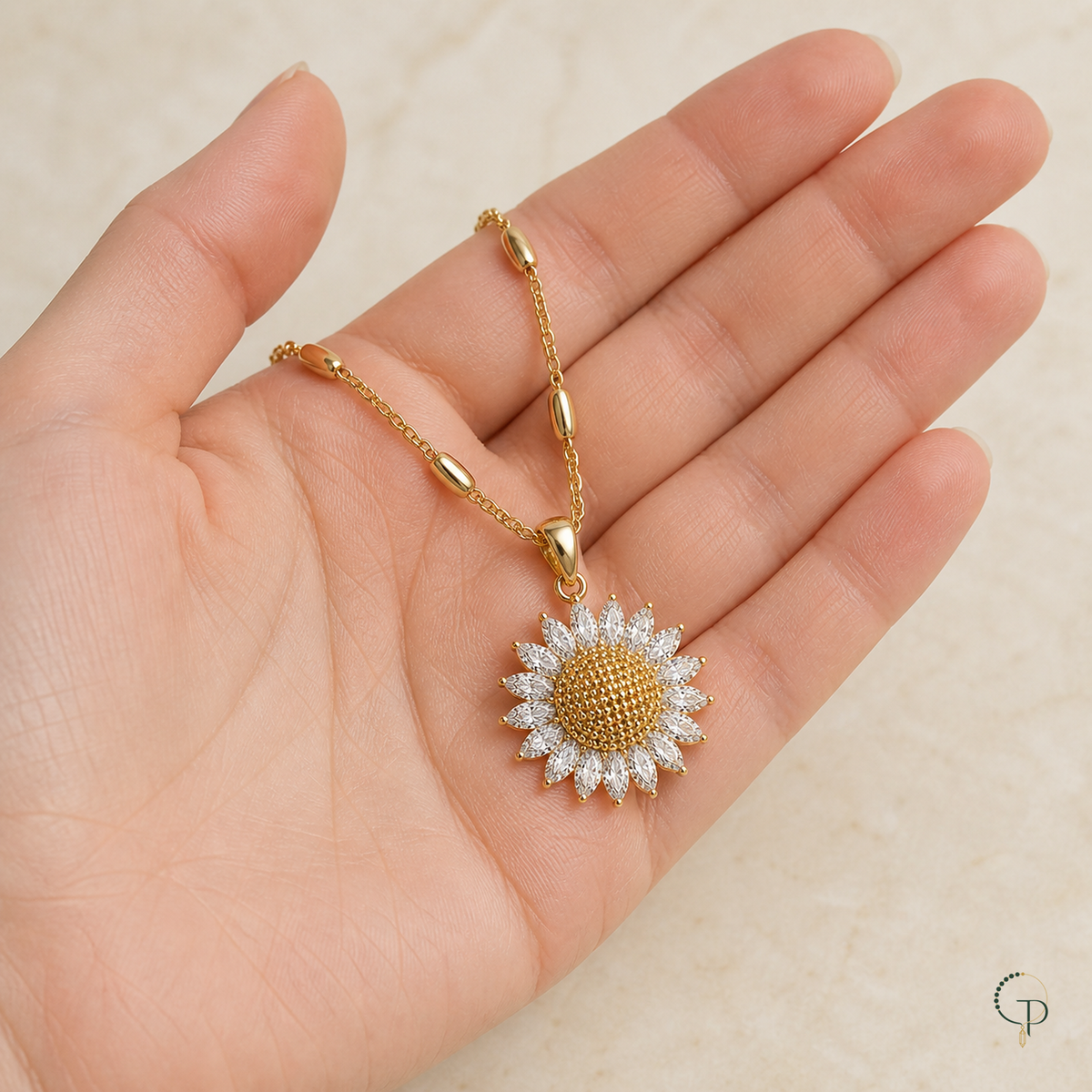 Sunflower pendant and polished station chain resting in an open hand for scale