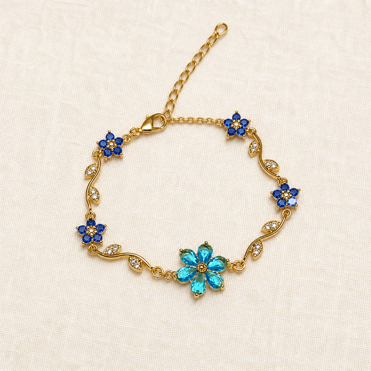 Full blue floral vine bracelet laid flat on warm ivory linen